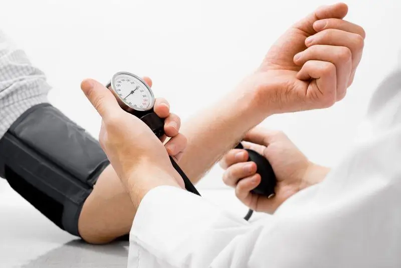 Hypertension artérielle symptômes : prise de la tension artérielle par un cardiologue lors d'une consultation médicale